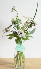 A selection of seasonal flowers in a glass bottle.