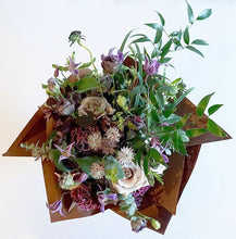 A bouquet full of seasonal summer flowers in a muted pink, lilac and raspberry color palette with lots of greenery and texture.  