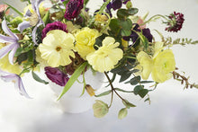 An arrangement bursting with seasonal flowers and foliage and is designed in a lush, asymmetric and horizontal style.  