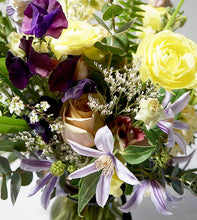 A flower jar bouquet full of seasonal flowers in a yellow, lilac and purple color palette with lots of greenery and texture