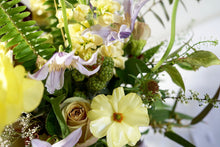 A flower jar bouquet full of seasonal flowers in a yellow, lilac and purple color palette with lots of greenery and texture