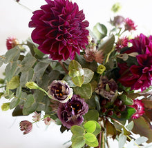 A bouquet full of seasonal flowers in shades of magenta and pink with lots of greenery and texture.