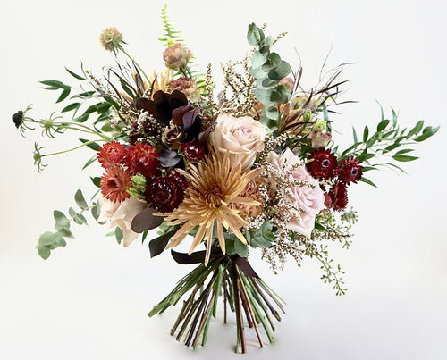 A bouquet full of seasonal flowers in warm autumnal colors.