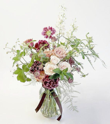 A flower jar bouquet full of seasonal summer flowers in shades of cappuccino, raspberry and scarlet with pops of white and pale pink and lots of greenery.